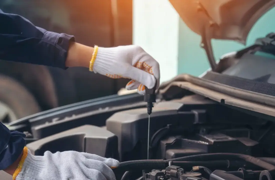 Mechanic checking the engine oil level on a dipstick during a car service