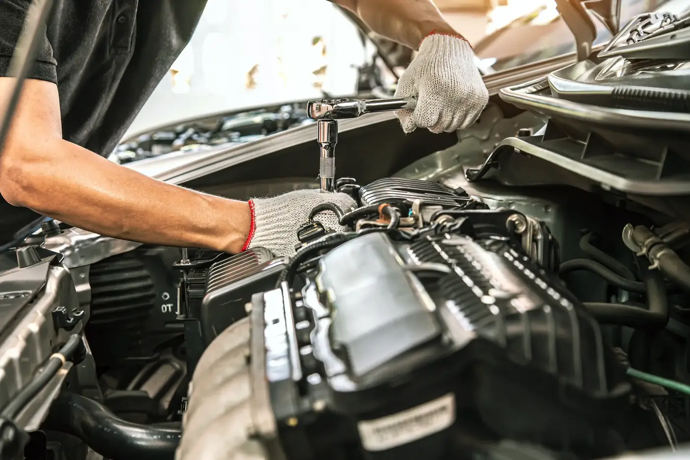 Mechanic working on a car engine with a ratchet
