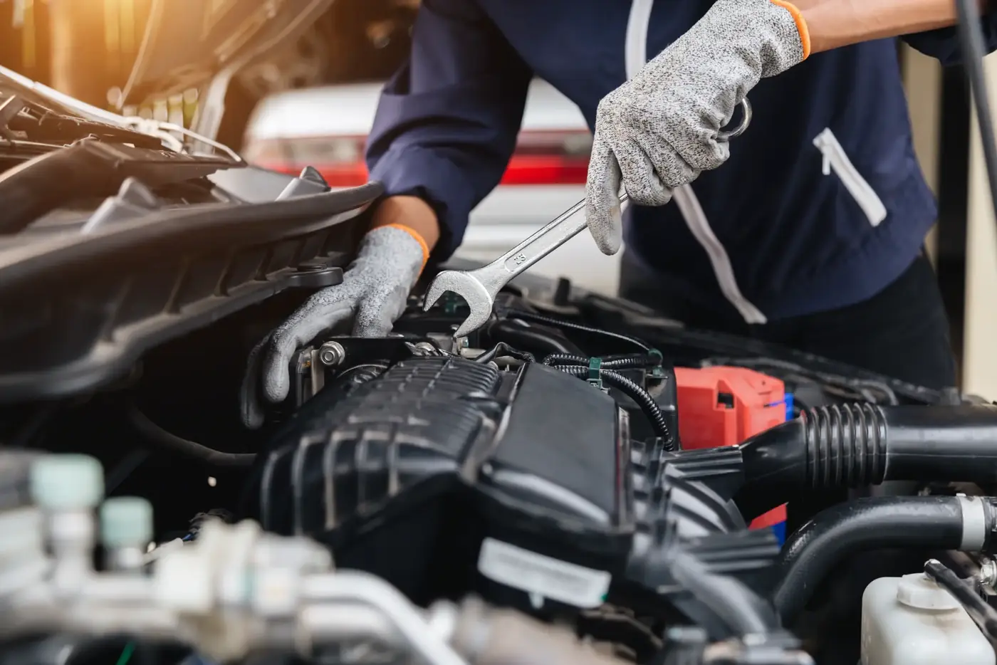 Mechanic tightening an engine fitting with a spanner under a car bonnet